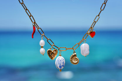 Necklace with various charms against a blue ocean background